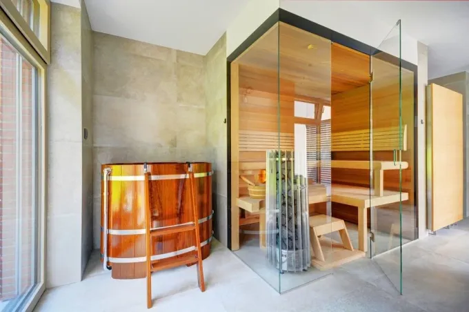 Celoprosklená finská sauna je vybavena saunovými kamny HELO Rocher a dotykovým ovládacím panelem HELO T1, zabudovaným ve skleněné stěně kabiny. Prosklená část má po obvodu černý potisk pro zakrytí stropní části a propojení s navazujícími materiály. Vnitřní obložení je tvořeno dřevěným cedrem, kvalita dřeva A+, lavice a zádové opěrky jsou vyrobeny z tepelně zpracované olše. Ochlazovací káď je vyrobena z tropického afrického dřeva kambala, s dvojitou perodřážkou pro dlouhodobou stabilitu produktu. 